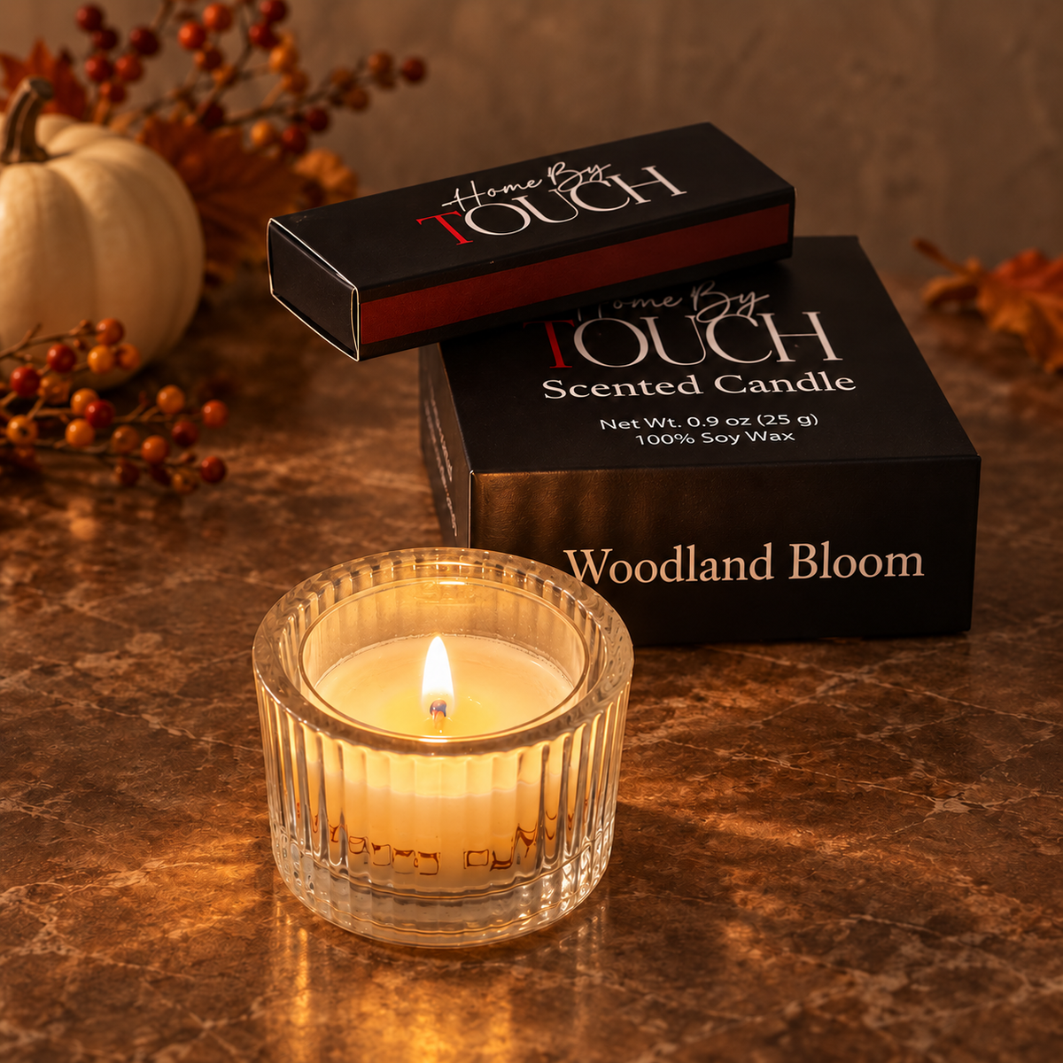 Woodland Bloom tea light glowing in a ribbed glass holder with Home By TOUCH packaging and luxury matches in a warm fall setting.