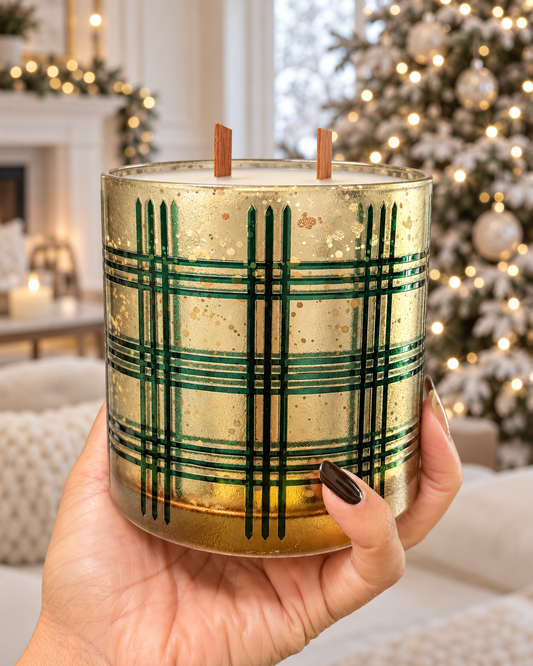 Traditional Pine green and gold candle held in hand in a winter setting